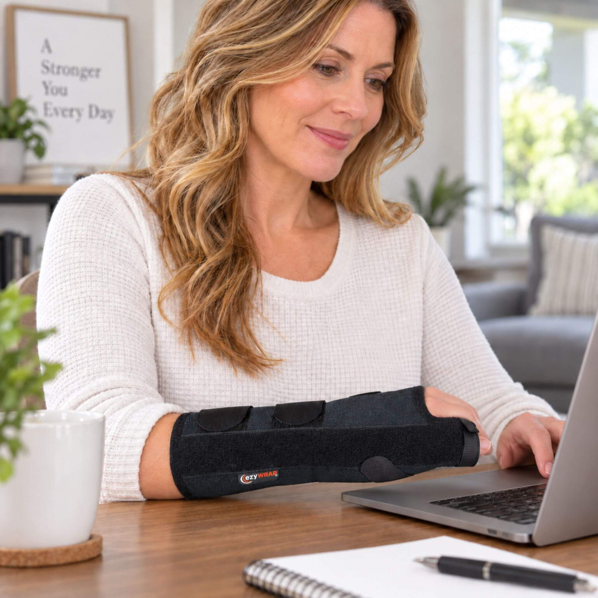 Woman wearing a right hand metacarpal fracture brace for hand, wrist and finger support indoors